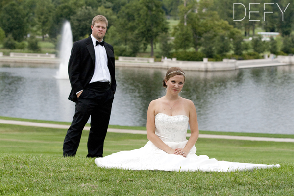 bride and groom in front of lake and fountain